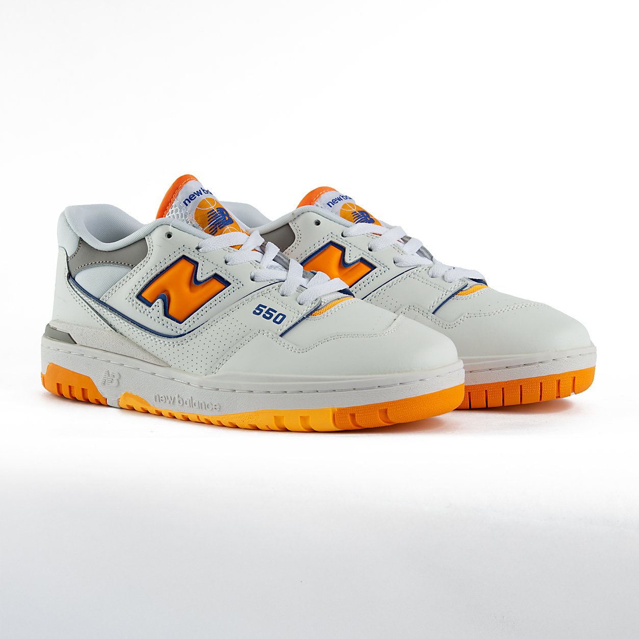 New Balance 550 sneakers in white with orange and gray details. A retro low-top shoe suitable for men and women.