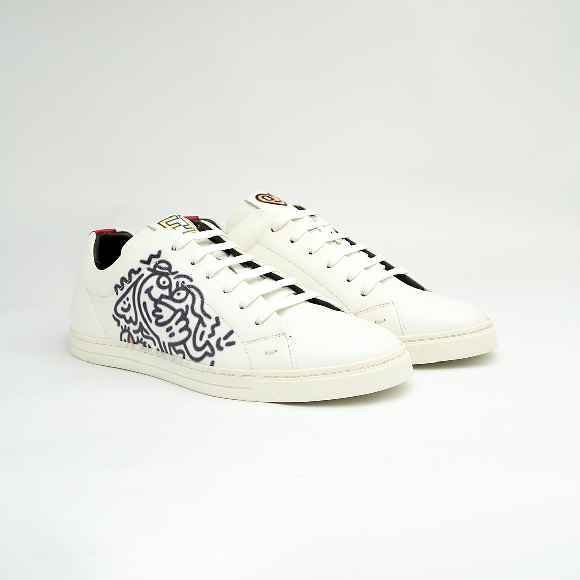 The White Tiger Skate Low is a clean, modern, low-top trainer with a luxury streetwear edge. It is crafted from smooth, premium white leather and features a distinctive black and white graphic drawing on the side panel, resembling a stylized tiger or abstract artwork.