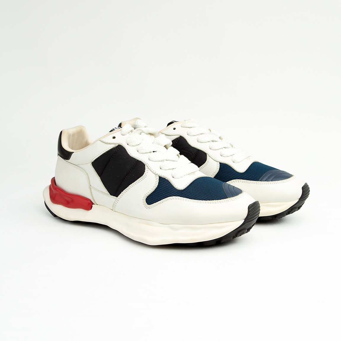This bold sneaker features sophisticated color blocking with a base of pristine white leather, accented by rich navy blue mesh on the toe box and side panels, and black suede/nubuck near the laces.