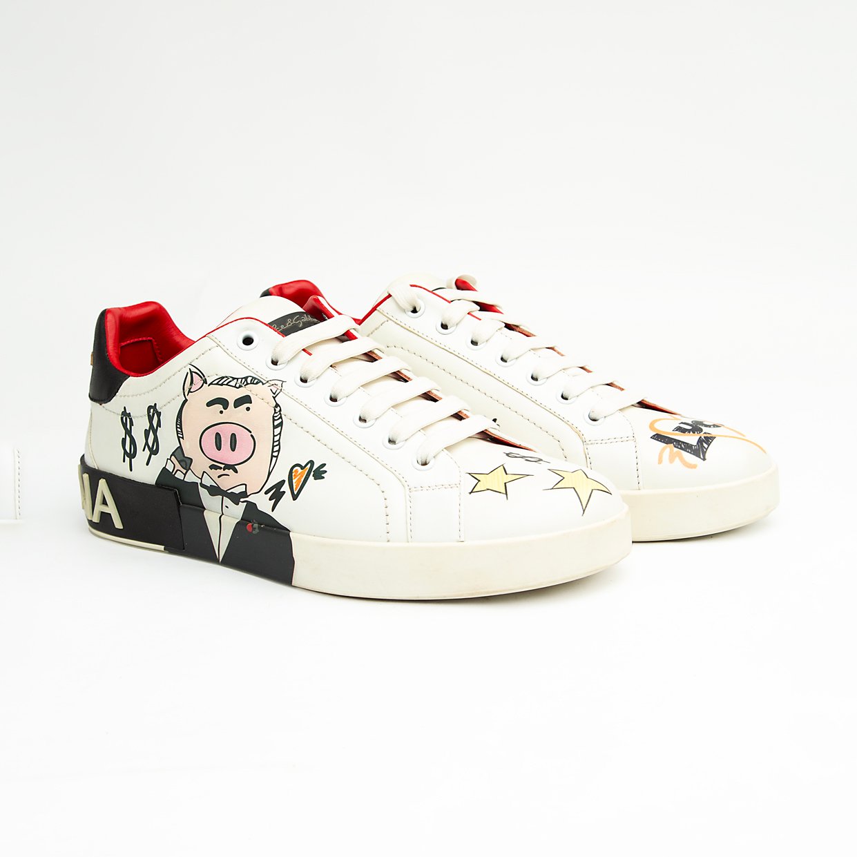 These pristine white leather sneakers are elevated by unique, vibrant hand-painted-style graphics, including the playful "Banker Pig" figure in a tuxedo, stylized money symbols, and bold star accents.